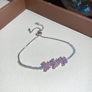 Elegante pulsera de tenis plateada con tres flores de circón rosa y cierre ajustable.