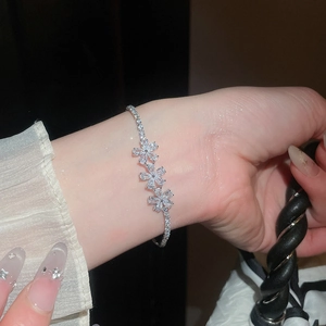 Primer plano detallado de una pulsera bañada en oro de 18k con tres flores de circonita