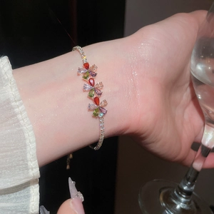Vista detallada de una pulsera bañada en oro de 18k con flores de circonita de colores en la muñeca