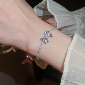 Detalle macro de una pulsera de tenis bañada en oro de 18k con un lazo de circón lila.