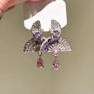 Detailed macro view of fan-shaped silver earrings with purple and pink zircon drops