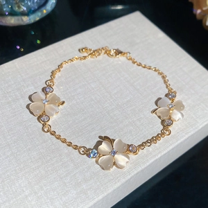 Detail eines eleganten goldenen Blumenarmbands mit Opal-Blütenblättern und Zirkonia-Steinen