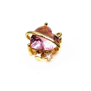 Macro detail of a heart-shaped pink crystal pendant with a gold Saturn ring accent
