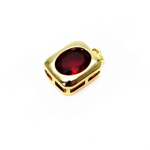 Detail showing a gold-plated rectangular charm with a large oval red zircon gemstone