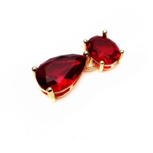 Close-up of red water-drop and oval zircon pendant with golden claw setting