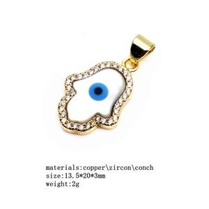 Detailed view of gold Hamsa pendant with zircon stones and blue shell Evil Eye detail