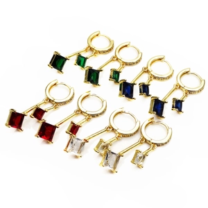 Detail van gouden oorbellen met micro-geplaveide vierkante zirkoon in diverse kleuren