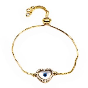 Macro detail of adjustable gold slider bracelet with pavé zircon heart and evil eye charm