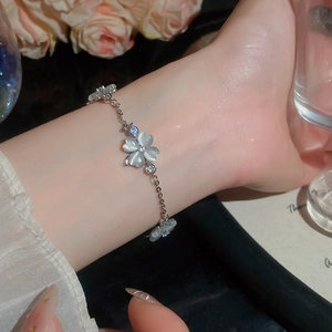 Detailansicht eines eleganten Blumenarmbands mit Katzenaugensteinen und Zirkonia am Handgelenk