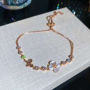Elegantes rotgoldenes Armband mit weißer Blume, Schmetterlingsanhänger und Zirkonsteinen.