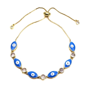 Detail van een gouden verstelbare evil eye armband met blauwe bedeltjes en fonkelende kristallen