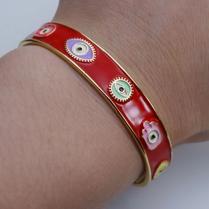 Detail of red enamel open bangle with colorful Evil Eye and Hamsa Hand charms