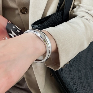 Close-up of silver-tone chunky geometric bangle on wrist with beige blazer