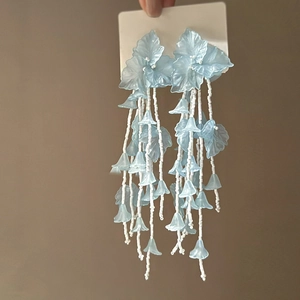Détail en gros plan de boucles d'oreilles élégantes en verre bleu clair à glands