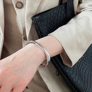Close-up of a silver irregular geometric bangle on a wrist with a stylish bag