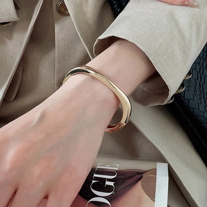Close-up view of a minimalist gold irregular geometric bangle worn on a woman's wrist
