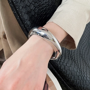 Close-up detail of a chunky silver metallic bangle with an irregular geometric design on a wrist