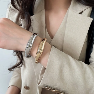 Detailed view of minimalist gold and silver metallic glossy geometric bangles on a model's wrist