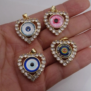 Detailed view of four colorful heart-shaped evil eye pendants held in hand for size comparison