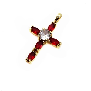 Detailed macro shot of a gold cross pendant with red marquise-cut stones and white zircon