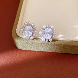 Primo piano di eleganti orecchini ovali in zirconia con bordo floreale di perle fini