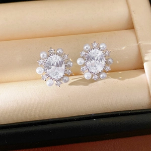 Dettaglio macro di eleganti orecchini ovali in zircone con halo di perle, placcati oro 14k