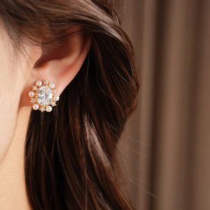 Primo piano di un elegante orecchino a clip con zircone ovale e perla indossato sull'orecchio
