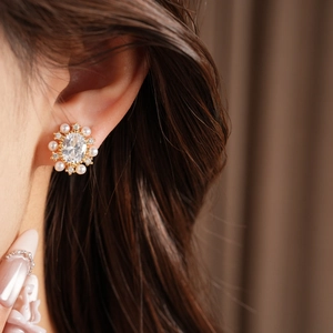 Primo piano di orecchini a clip in oro 14k con zircone ovale e perle indossati dal modello