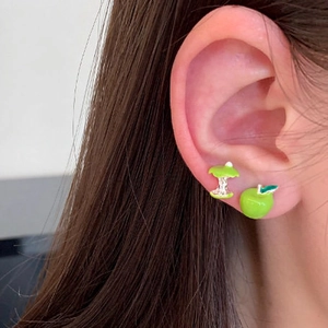 Close-up of asymmetrical green apple stud earrings worn on ear for detail view