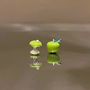 Detailed macro view of asymmetric green apple and apple core enamel stud earrings
