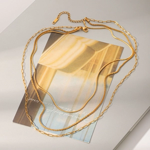 Detail shot of a triple-layered 18k gold plated stainless steel necklace on a prop.