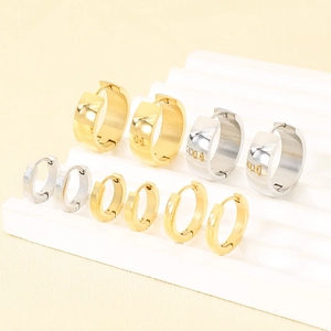 Close-up detail of polished stainless steel hoop earrings in multiple gold and silver sizes