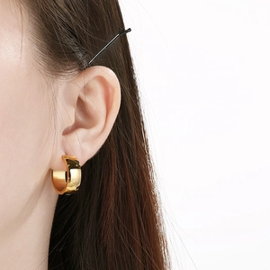 Close-up of minimalist gold stainless steel hoop earring worn on ear model