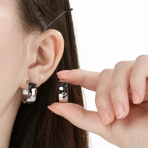 Detailed view of polished stainless steel wide hoop earrings worn for a daily look.