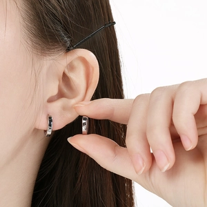 Close-up macro view of minimalist polished stainless steel hoop earring on model ear