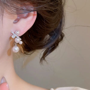 Detailopname van elegante Franse pareloorbellen met fonkelende strassteentjes op oor