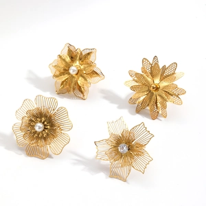 Anelli a fiore filigranati oro con perle e cristalli su sfondo bianco pulito