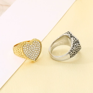 Primer plano de anillos de corazón de acero inoxidable oro y plata con pavé de cristales
