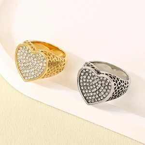Detalle macro de anillos de acero en oro y plata con corazón pavé y banda de rejilla
