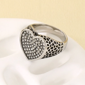 Primer plano detallado de un anillo de corazón en acero con piedras pavé y diseño calado.