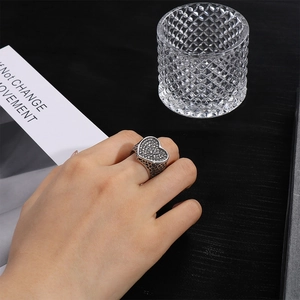 Vista detallada de anillo corazón pavé con textura malla vintage en mano
