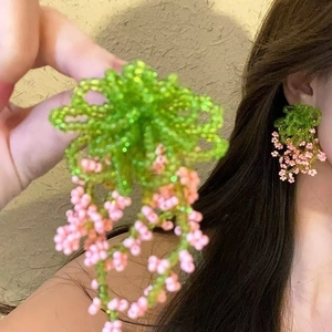 Close-up of handmade beaded flower tassel earrings in green and pink floral design