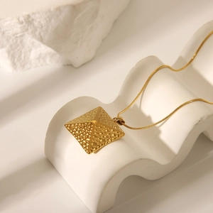 Detailansicht eines goldenen Edelstahl-Pyramidenanhängers an einer feinen Schlangenkette