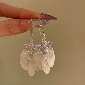 Detailed view of shimmering zircon and mother-of-pearl shell tassel earrings in resort style
