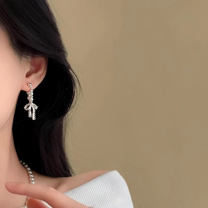 Primo piano dettagliato di eleganti orecchini a fiocco d'argento con perle finte
