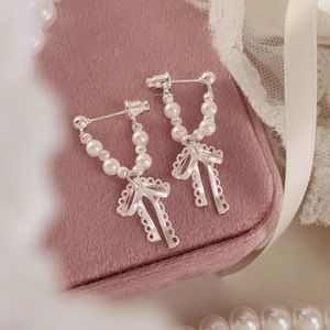 Primo piano dettagliato di orecchini a fiocco d'argento con delicate perle finte bianche