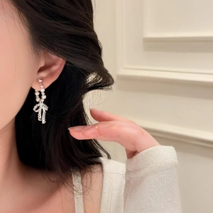 Primo piano di eleganti orecchini a fiocco con perle indossati da una modella con stile