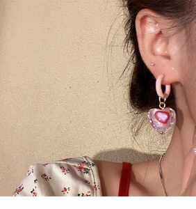 Detailansicht eines modischen Retro-Ohrrings mit rosa Herzanhänger, getragen am Ohr