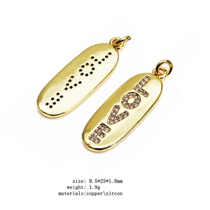 Détail du pendentif LOVE doré avec incrustation de zircon et gravure braille élégante