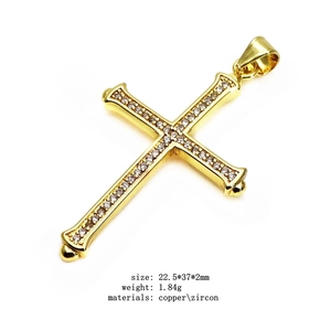 Macro detail of gold plated copper cross pendant with white zircon micro-inlay accents